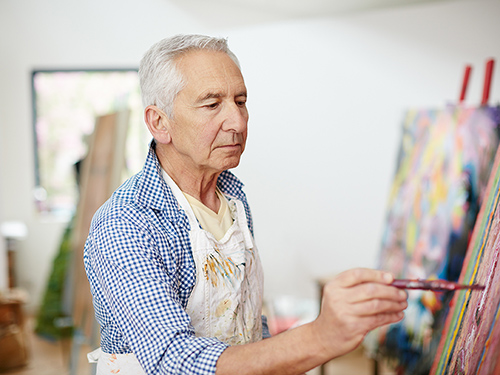 Man enjoying free time in retirement taking up his favorite hobby of painting. >